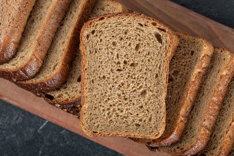 A wooden cutting board with slices of bread . High quality photo